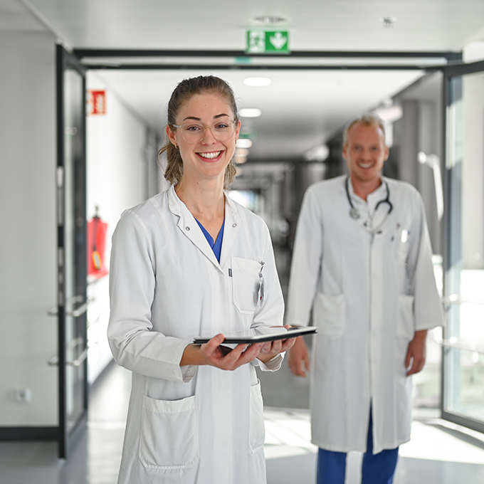 Ärztin steht gemeinsam mit Kolleginnen und Kollegen auf dem Krankenhausflur