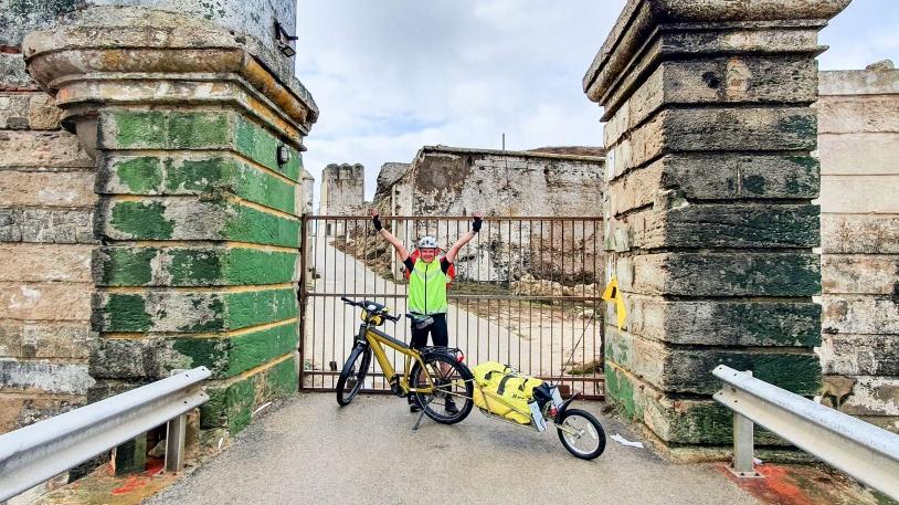Wolfgang Bär in Tarifa mit hochgestreckten Armen hinter seinem Fahrrad stehend 